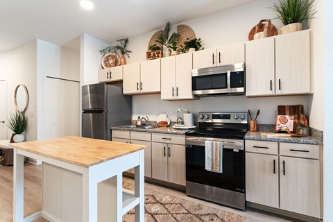 A kitchen with a wooden table and stainless steel appliances.