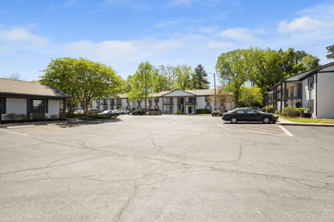 A parking lot with a car parked in front of a building with a white facade.