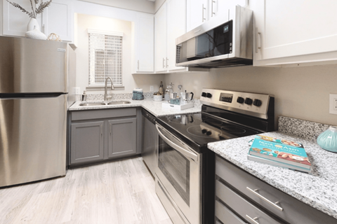 A modern kitchen with a stainless steel refrigerator, microwave, and oven.