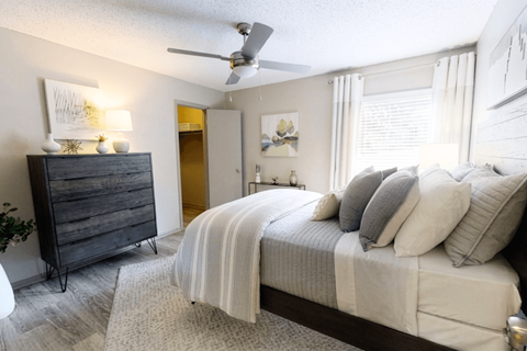 A bedroom with a bed, dresser, and ceiling fan.