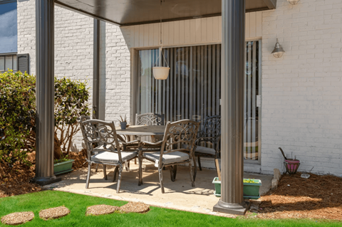 A patio with a table and chairs is covered by a white awning.