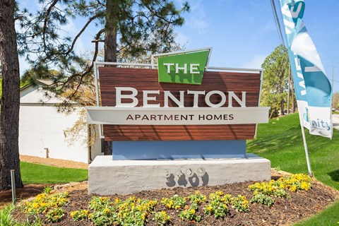 A sign for The Benton Apartment Homes is displayed in front of a building.