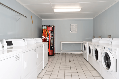 A laundromat with a Coca-Cola machine in the corner.