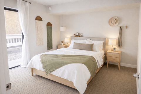 A bedroom with a large bed and a window with curtains.