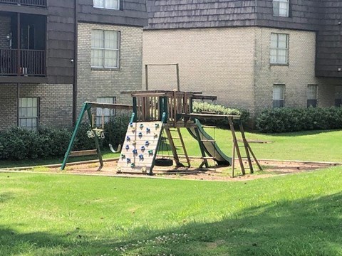 A playground with a slide and a climbing frame in a grassy area.