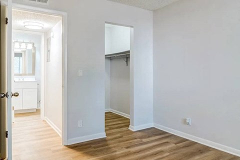 A white room with a wooden floor and a door leading to another room.