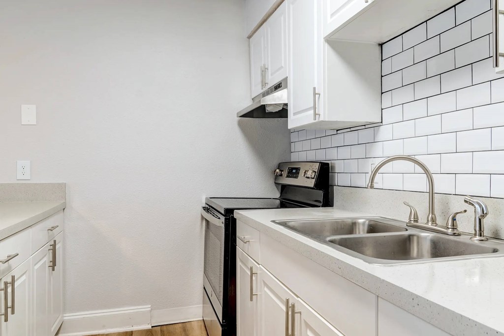 A kitchen with a black oven and white cabinets.