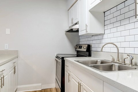 A kitchen with a black oven and white cabinets.