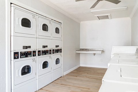A row of white front loading washing machines in a laundry room.