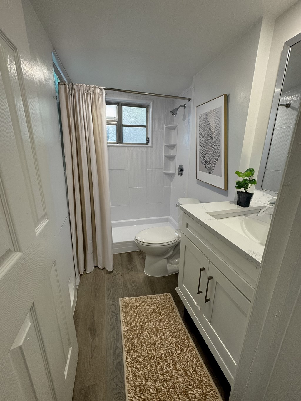 A bathroom with a toilet, sink, and a rug on the floor.