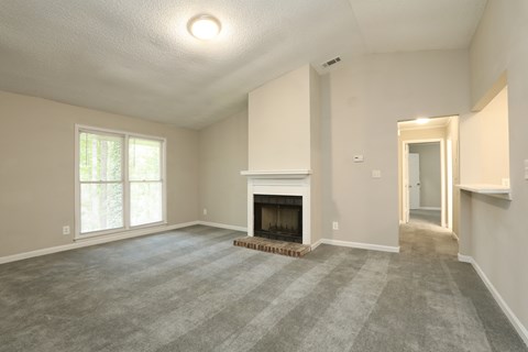 A spacious living room with a fireplace and a carpeted floor.