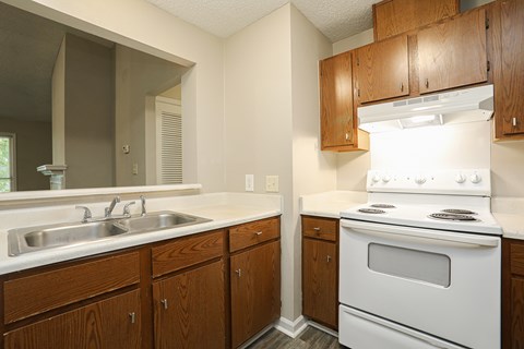 A kitchen with a white stove and wooden cabinets.