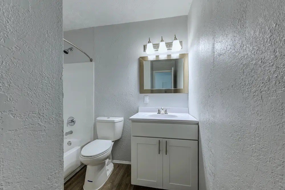 A white bathroom with a toilet, sink, and mirror.