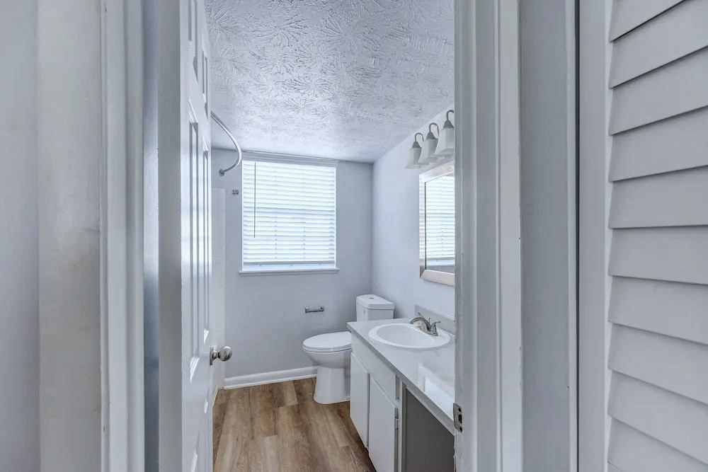A white bathroom with a toilet, sink, and window.