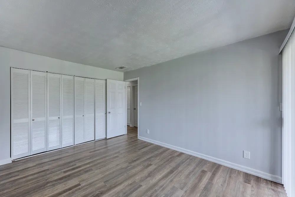 Closet with white doors and wooden floor in a room.