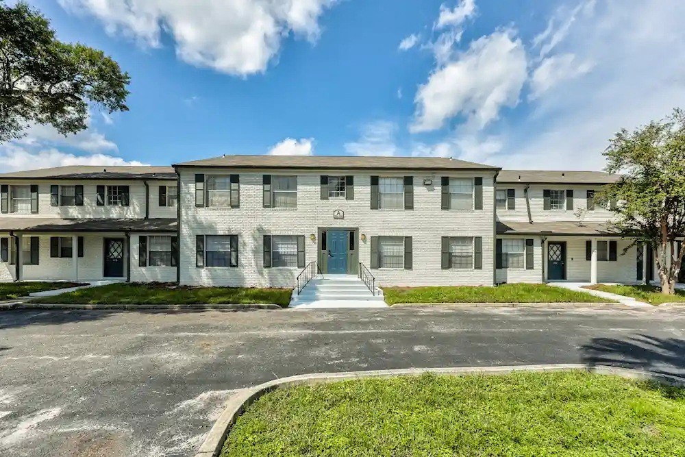 A building with a green lawn in front and a tree to the left.