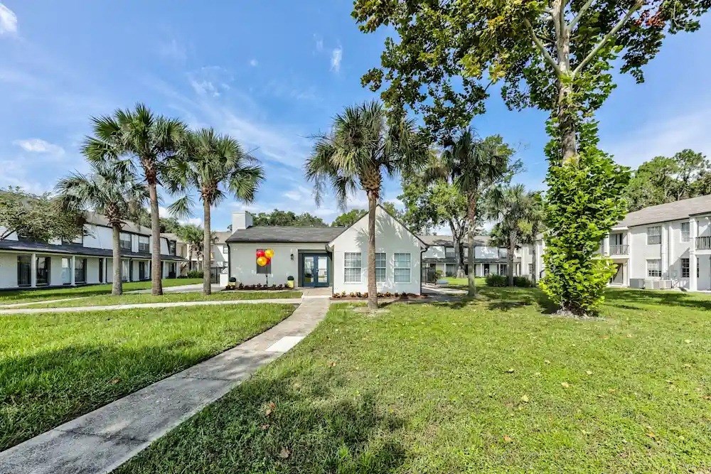 A residential area with a clear blue sky and a pathway leading to a house with a red sign.