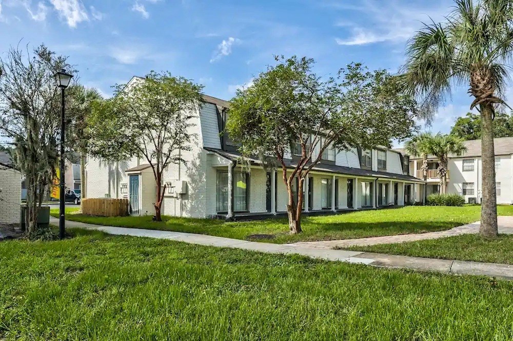 A white building with a green lawn in front.