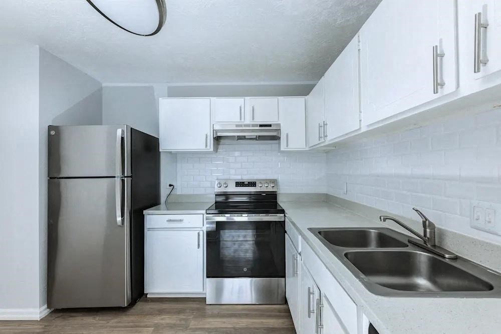 A modern kitchen with a stainless steel refrigerator, oven, and sink.