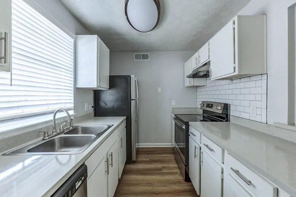 A kitchen with white cabinets and a black fridge.