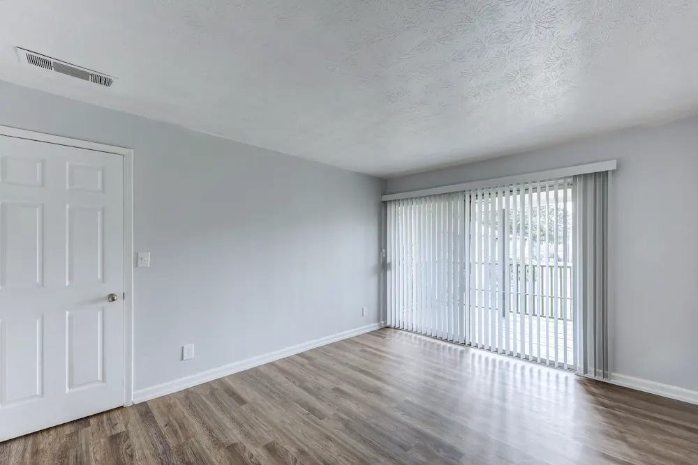 A room with a white door and a window with blinds.