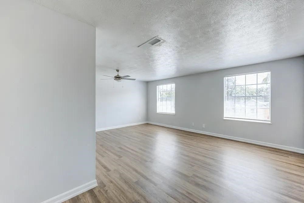 A room with a ceiling fan and two windows.