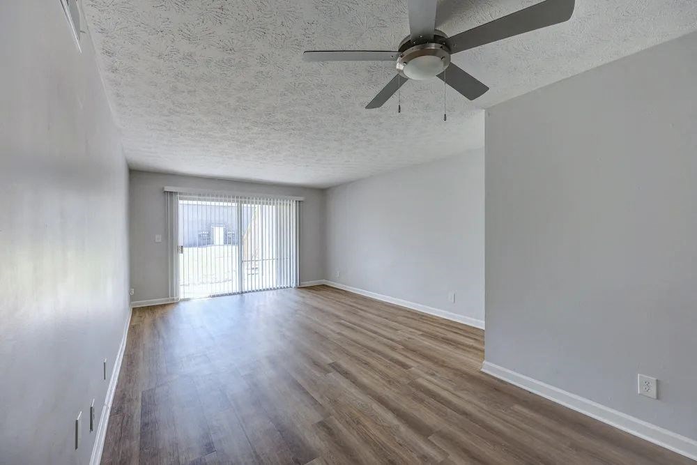 A room with a ceiling fan and wooden flooring.