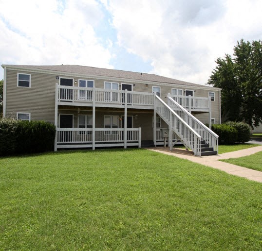 the back of an apartment building with a porch and a lawn