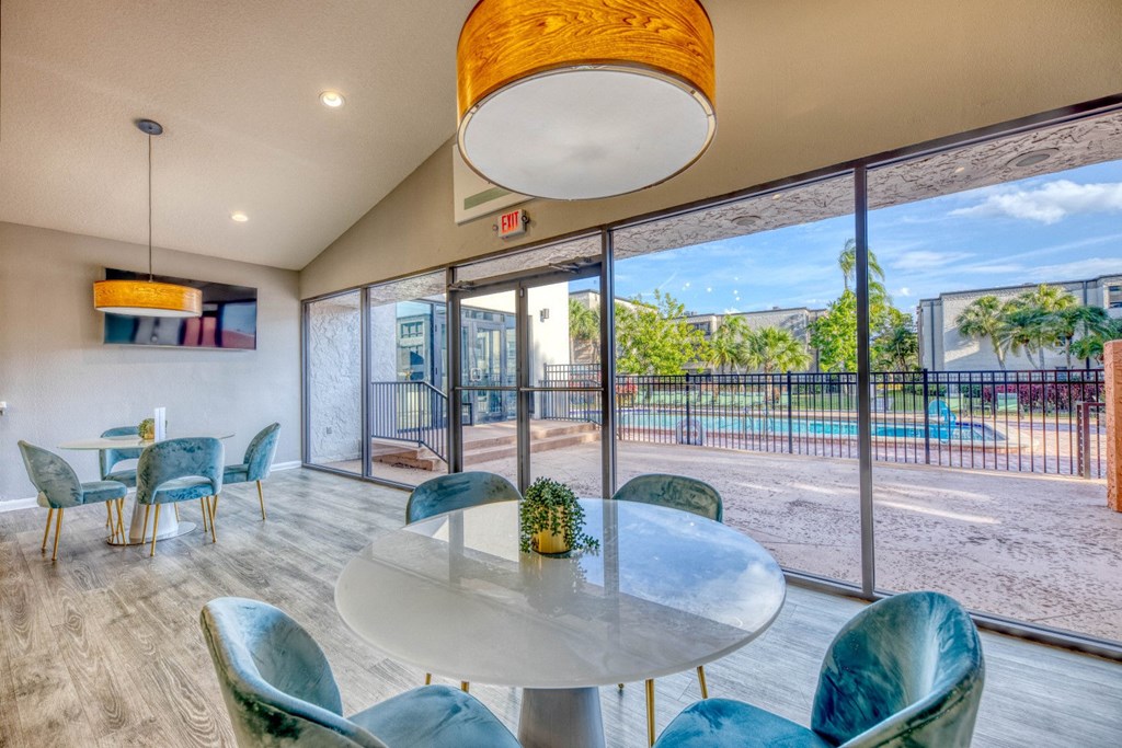 A modern dining area with a glass wall overlooking a pool.