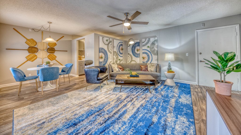 A living room with a blue rug and a ceiling fan.