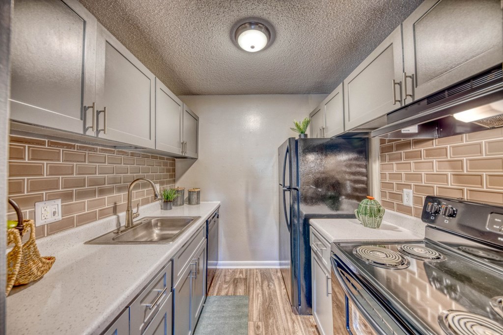 A kitchen with a stove, sink, and refrigerator.