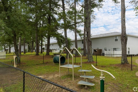 A playground with a slide, swings, and a seesaw in a fenced area.