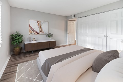 A bedroom with a large bed and a wooden cabinet.