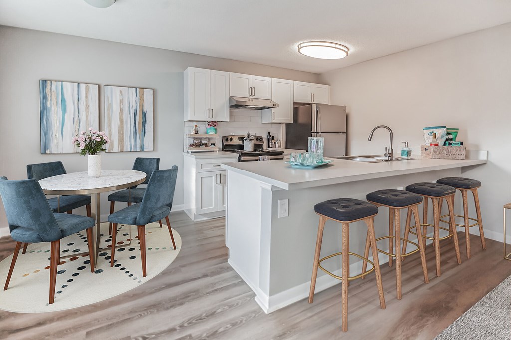 A kitchen with a white counter and blue chairs.