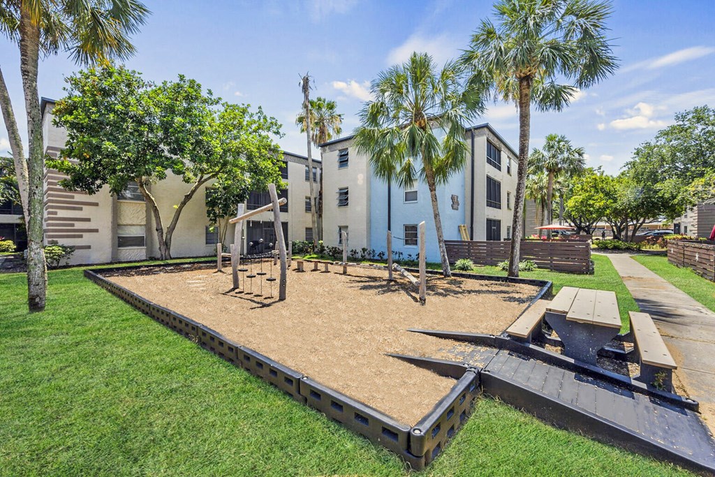 A playground with a slide and a sandbox in the foreground.