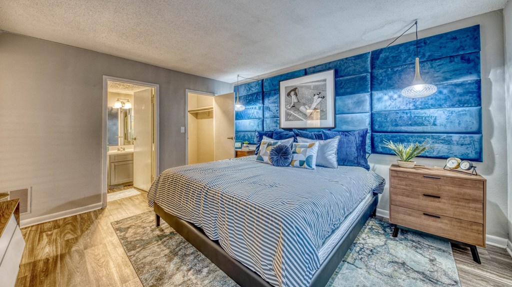 A bedroom with a bed, nightstand, and a painting on the wall.