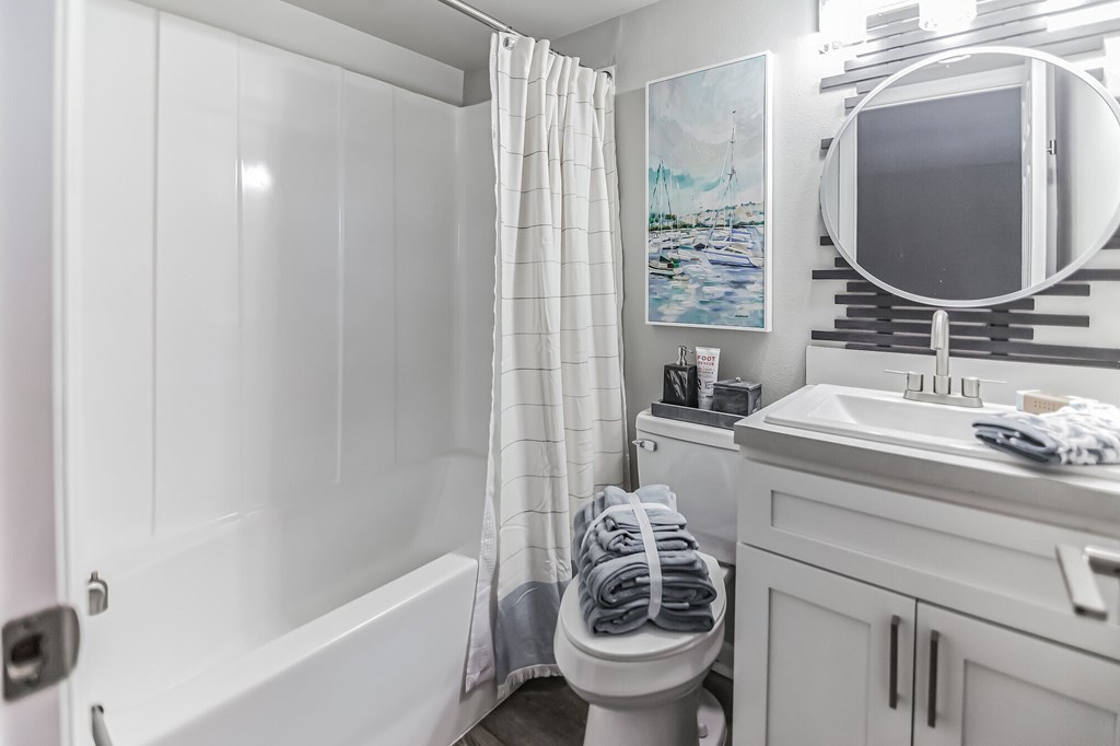 A white bathroom with a towel hanging on the toilet.