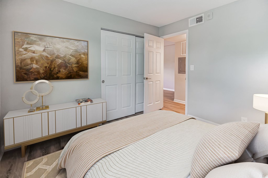 A bedroom with a large bed and a painting on the wall.