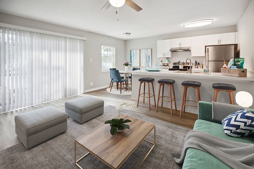 A modern living room with a kitchen area in the background.