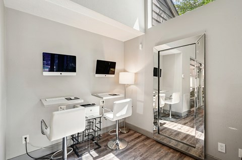 A modern bathroom with a vanity, mirror, and two chairs.