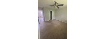 A room with a ceiling fan and carpeted floor.