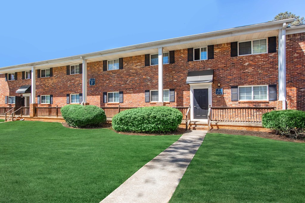 A brick building with a white roof and a green lawn in front.