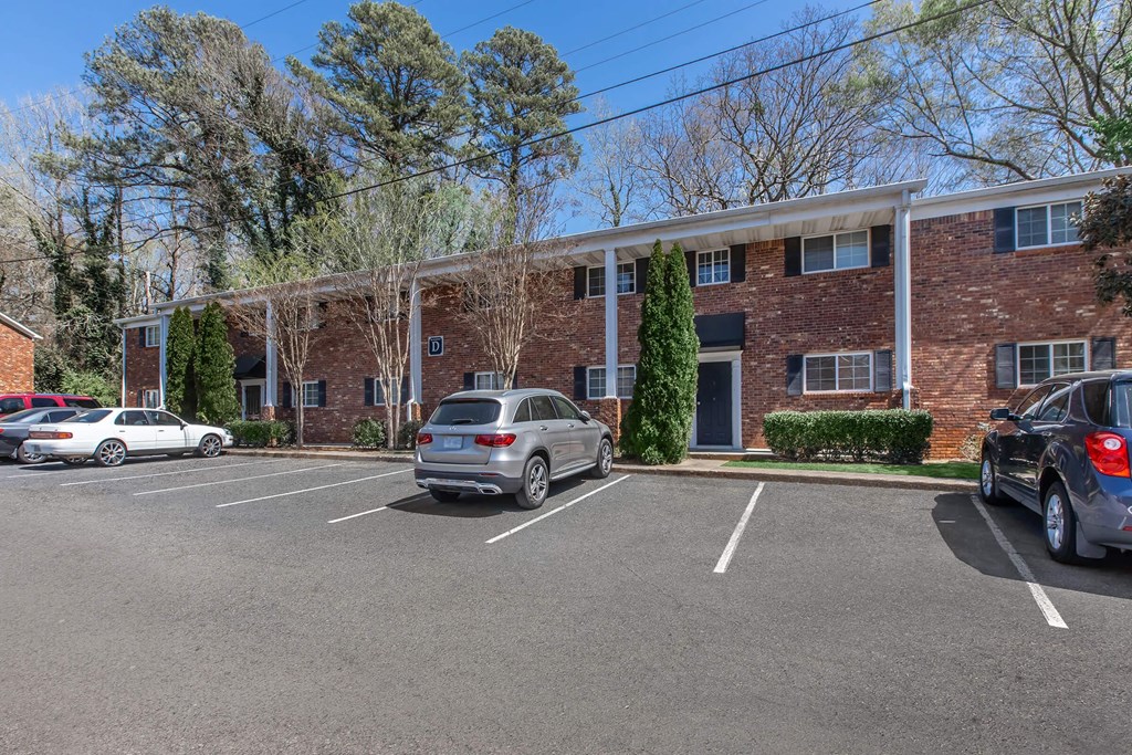 A parking lot with cars and a brick building in the background.