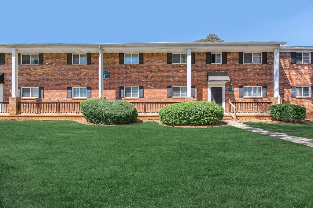 A red brick building with a green lawn in front.
