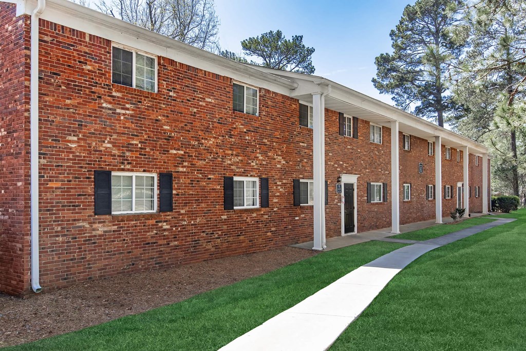 A long brick building with white trim and a white walkway in front.