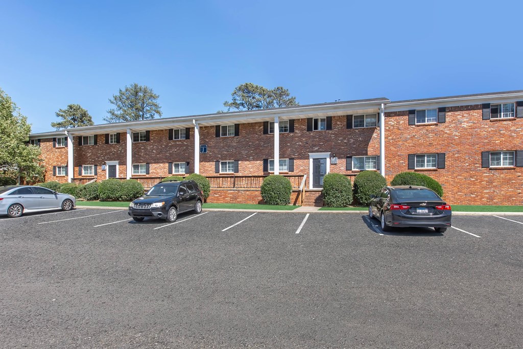 A parking lot with cars and a brick building in the background.