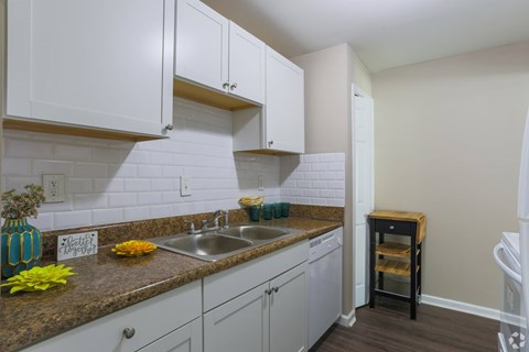 A kitchen with white cabinets and a brown countertop.