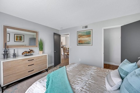 A bedroom with a large bed and a dresser with a mirror above it.