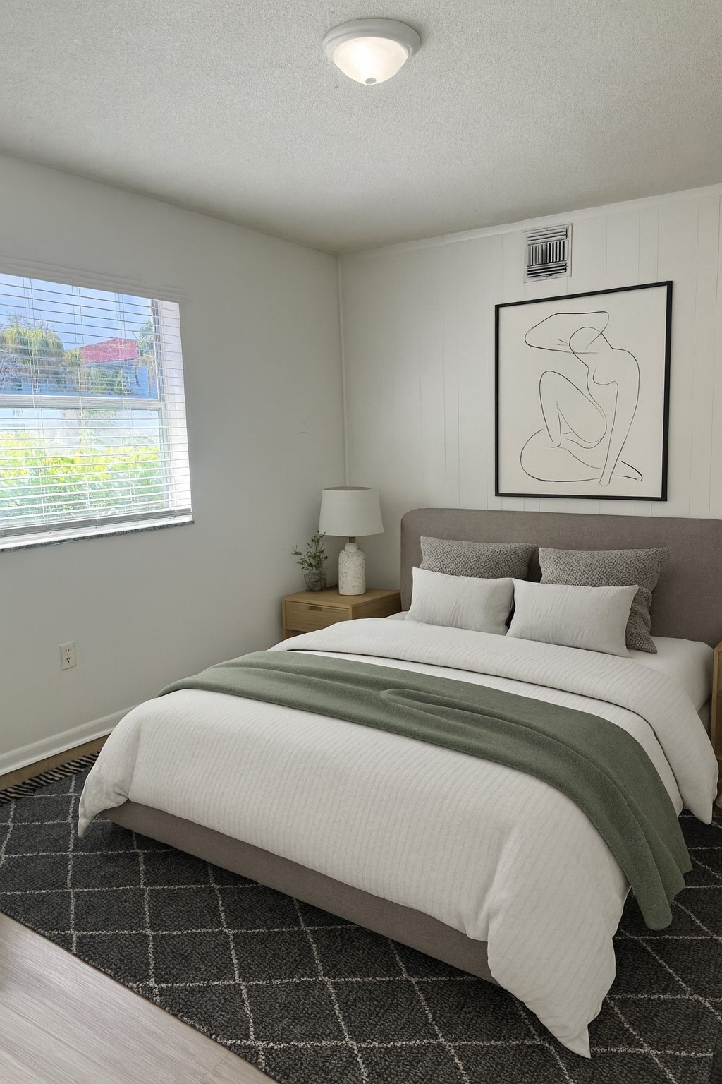 A bedroom with a large bed and a framed picture on the wall.