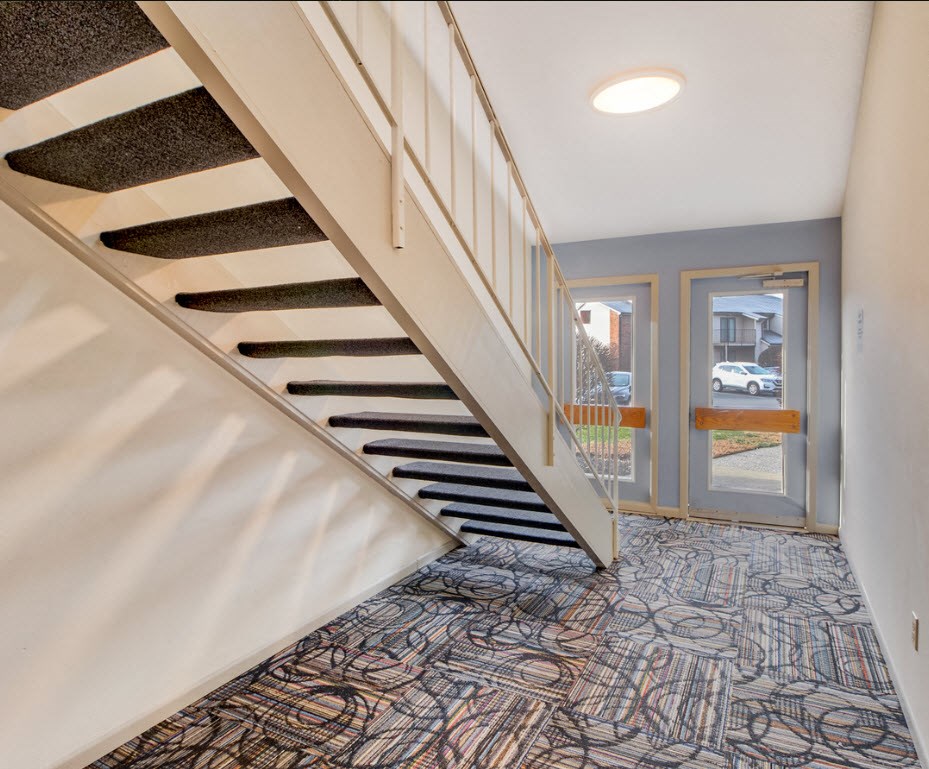 A staircase with a carpeted floor and a glass door at the bottom.